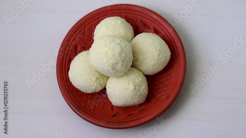 Yummy Kachagolla sweets rest on a clay plate, set against wooden backdrop. Kanchagolla, a beloved Bengali delicacy, is prized for its soft, spongy texture and subtle sweetness.