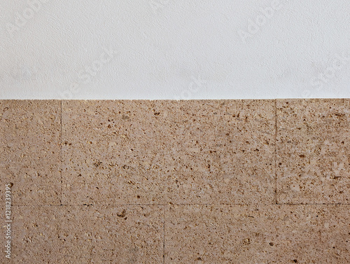 Smooth white wall texture background with yellow peach pink orange fossiliferous sandstone slabs cladding. Interior and exterior decoration with rustic mediterranean style textured stone rock tiles.