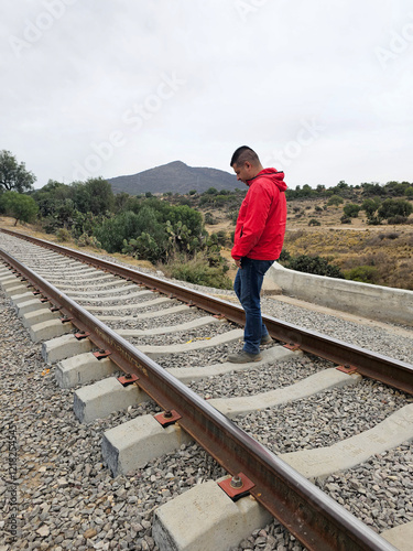 Dark-skinned Latino adult man walks along the border train tracks to cross the border as an undocumented person to fulfill the American dream photo