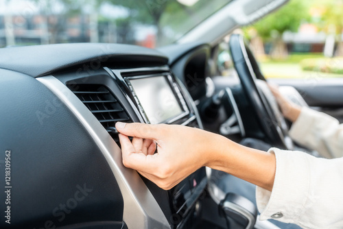 Female hand checking air conditioning panel inside car.