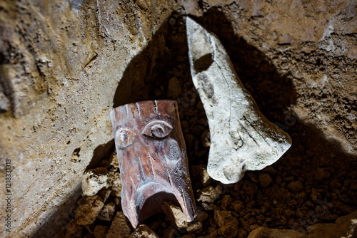 Figurine of an ancient deity and a tool made of animal bone on the ground, a magic ritual