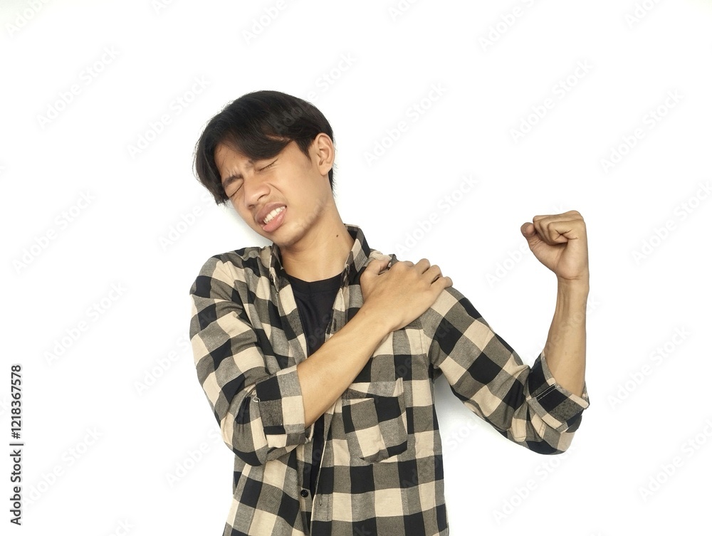 Young Asian man touches his left shoulder with a pained expression Young Asian man touches his left shoulder with a pained expression