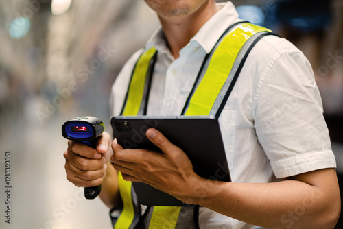 A man wearing a safety vest is holding a tablet and a barcode scanner. He is likely working in a warehouse or a similar environment where he needs to scan items for inventory or tracking purposes photo