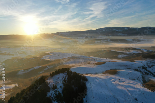 Aerial view of sunset over misty winter mountains