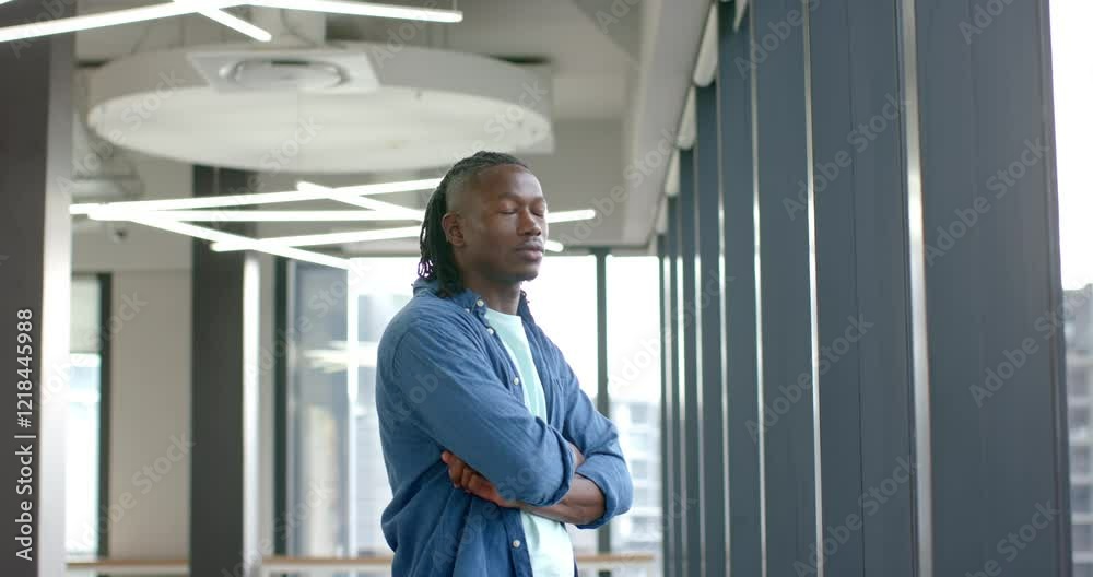 Confident man standing with arms crossed in modern office building Confident man standing with arms crossed in modern office building
