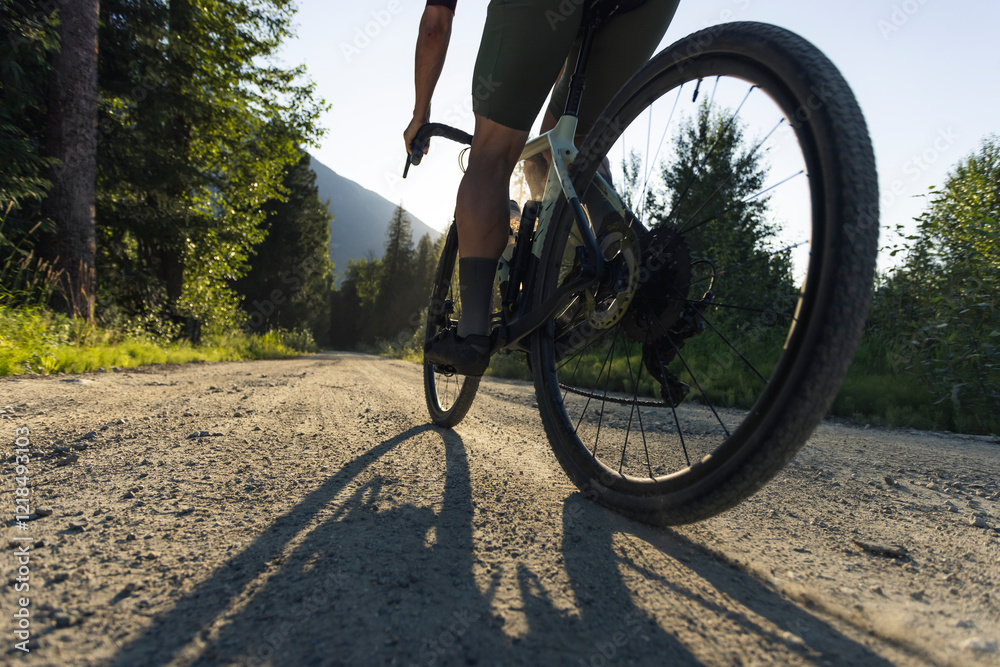 © Cavan Images - Close up of gravel bike tire riding down a dirt road at golden hour