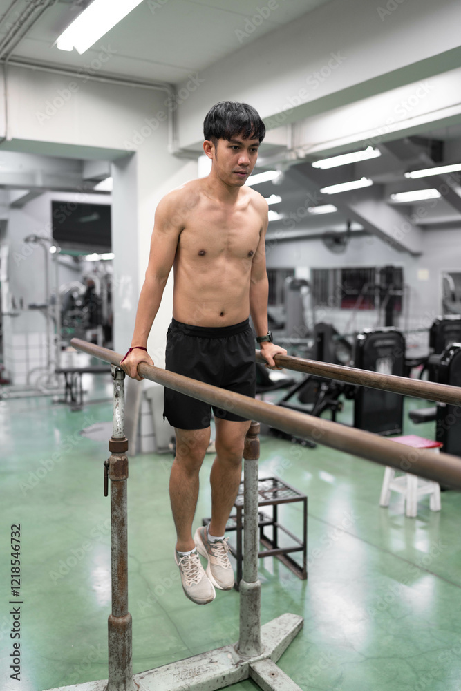 Fototapeta premium Asia young man warm up or exercising on parallel bars at gym