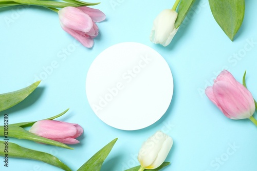Beautiful fresh tulips with paper card on color background