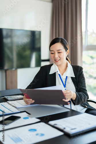 Busy 40 years old business woman working in office checking documents. Mid aged businesswoman accounting manager executive or lawyer using laptop reading paper file financial report, tax invoice. photo