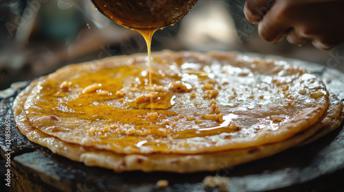 Close-up of a puran poli being garnished with ghee, symbolizing the festive richness of Ganesh Chaturthi cuisine 