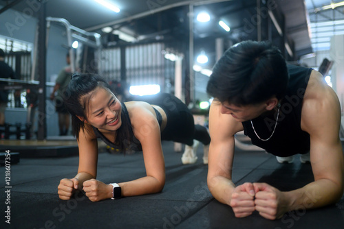 Personal trainer and and female client maintaining planks on the gym floor