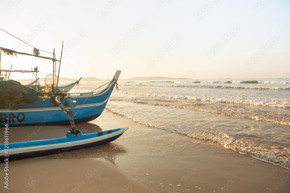 Fototapeta premium Surfing Paradise and golden beach in Weligama coast of indian ocean in Sri Lanka. Fishing boat on the beach in the morning, Sri Lanka.