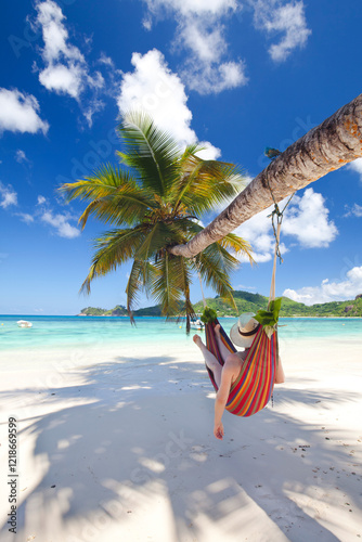 relaxed woman in a colorful hammock on the beach, recreation on Seychelles island