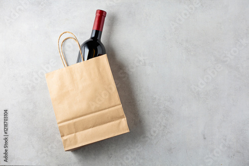 Bottle of red wine in a paper bag on a white stone background. photo