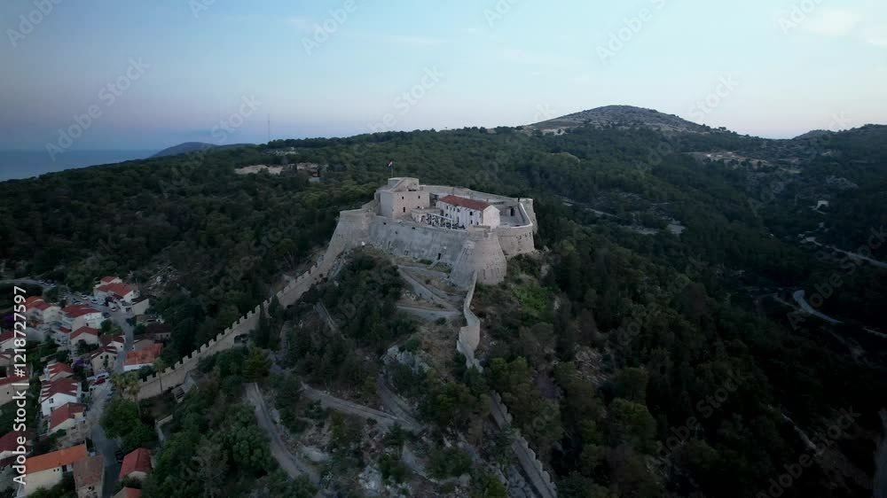 Orbit drone shot of Hvar castle on top of the hill with a forest at sunrise in Croatia Orbit drone shot of Hvar castle on top of the hill with a forest at sunrise in Croatia