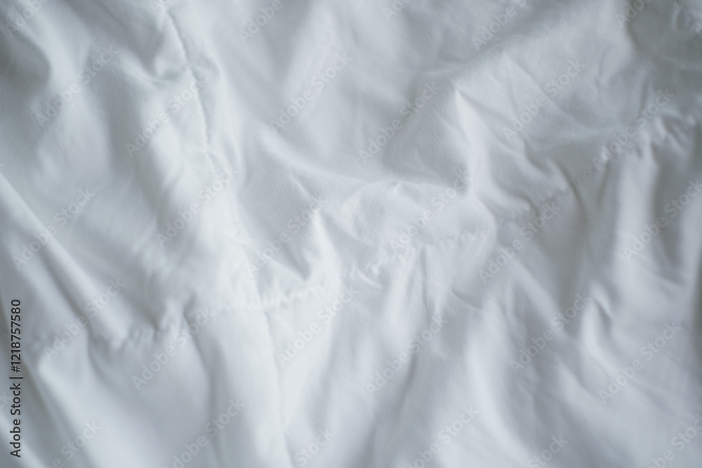 Fototapeta premium Closeup of beautiful white shiny crumpled fabric sheets on the bed