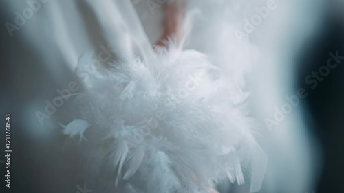Female hands in a white robe with feathers