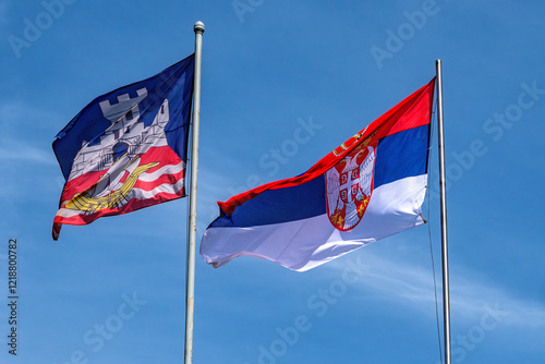 Serbian national flag and city emblem flag of Belgrade against blue sky
