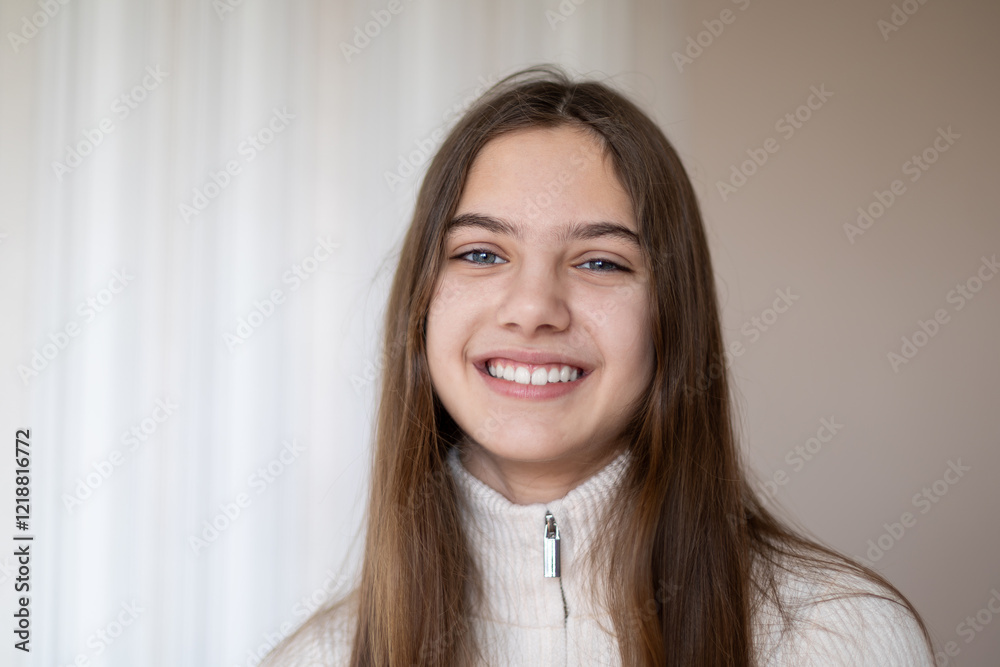 Smiling girl in a white sweater with long brown hair. A young girl with long brown hair and a bright smile poses in front of a neutral background, radiating happiness and confidence. Smiling girl in a white sweater with long brown hair. A young girl with long brown hair and a bright smile poses in front of a neutral background, radiating happiness and confidence.