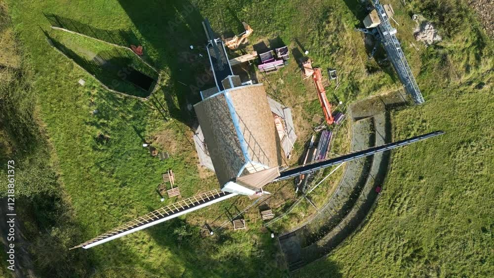 newly built vintage windmill's blades majestically rise against sunny sky gansakkermolen belgium perspective dynamic upward aerial drone shot birdseye view 