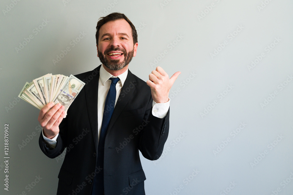 Happy businessman showing money and pointing with thumb Happy businessman showing money and pointing with thumb
