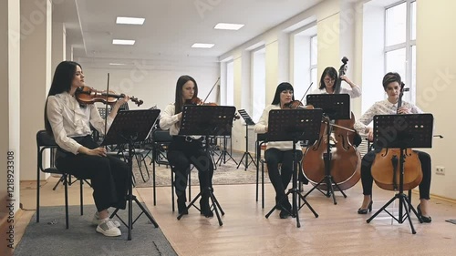 String quintet performing in vibrant hall. Dynamic energy flows through passionate musicians, creating live music experience. Quintet synchronizes strings to craft emotional, captivating sound