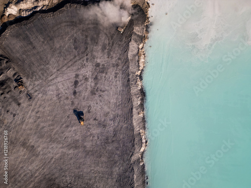 Schilderij op canvas A cement factory tailings site with heavy machinery operating near a turquoise lake