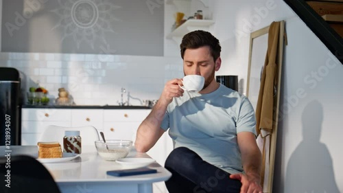 Pensive man drinking tea at morning kitchen closeup. Guy sipping hot beverage