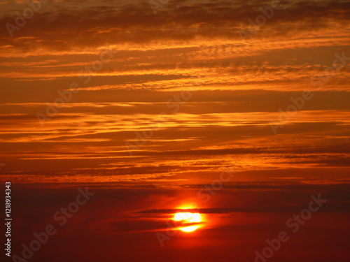 il sole al tramonto in un cielo rosso e arancione photo