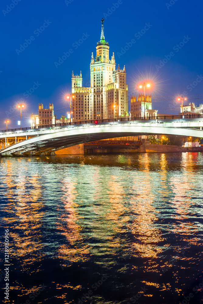Obraz premium A high-rise building on Kotelnicheskaya embankment and Bolshoy Ustinsky bridge at night. Moscow