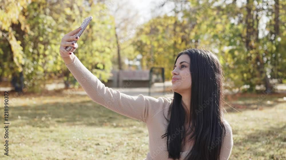 Young woman taking selfie in autumn park using smartphone Young woman taking selfie in autumn park using smartphone