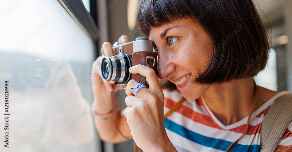 Fototapeta premium train travel. Young woman enjoying a train ride with a camera. tourist takes pictures of beautiful tourist places on camera. film camera.