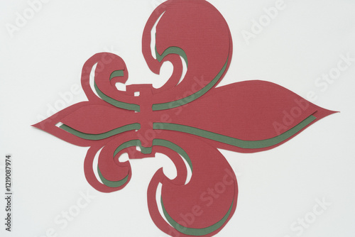 overlapping fleur-de-lys shapes machine-cut from red and green paper on a blank surface photo