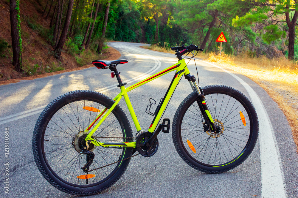 Fototapeta premium Generated imageA bright yellow mountain bike on a winding road in a picturesque forest in a mountainous area. Perfect for travel, active lifestyle and outdoor adventures.