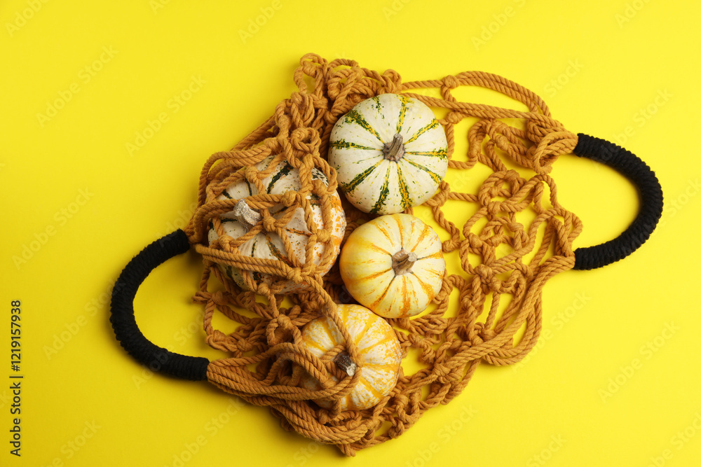 Macrame shopping bag and pumpkins on yellow background, top view Macrame shopping bag and pumpkins on yellow background, top view