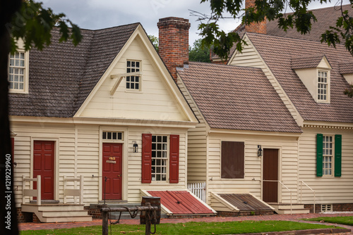 Typical ancient wooden Houses with Sidewalk and green Grass in Foreground in Colonial Williamsburg, Open Air Museum