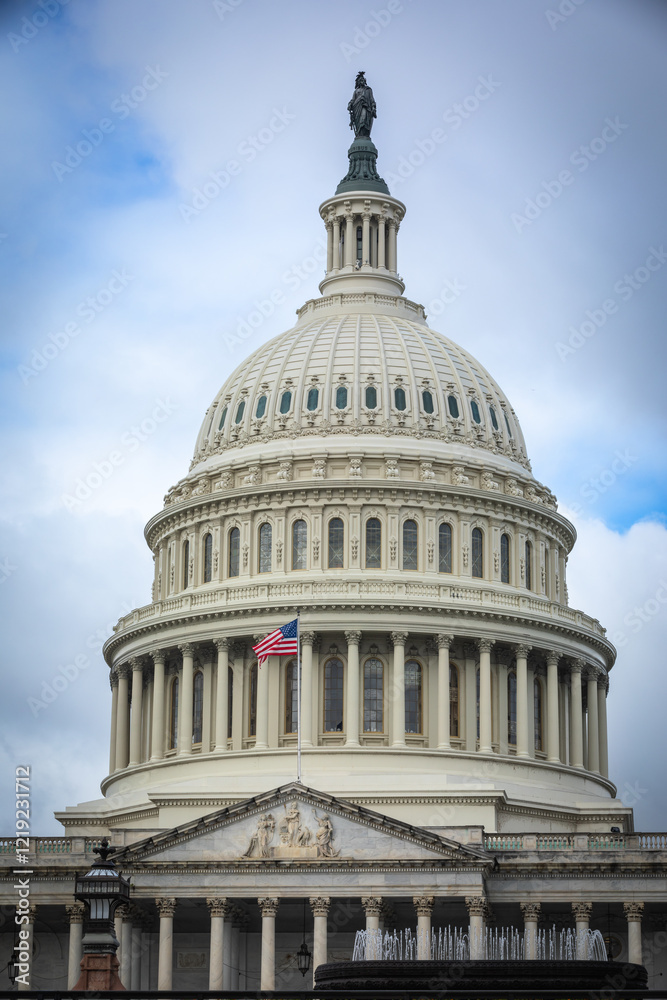 Fototapeta premium US Capitol Building in Washington, DC - Partial View of the Dome with US Flag; bright Clouds in Background; Close-up