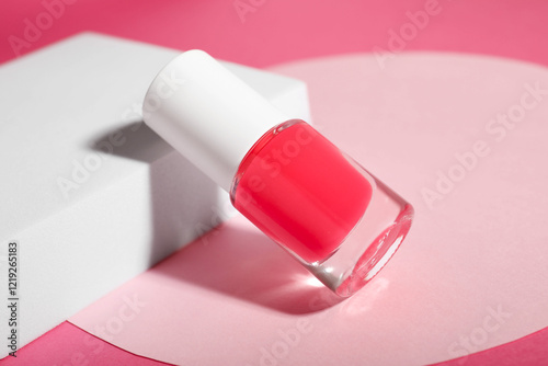 Stylish presentation of nail polish in bottle on pink background, closeup photo