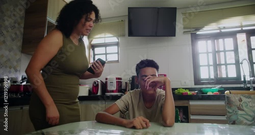 Mother removing phone from teenage son during disagreement about screen time, addressing overuse and setting boundaries, showcasing family conflict and discipline