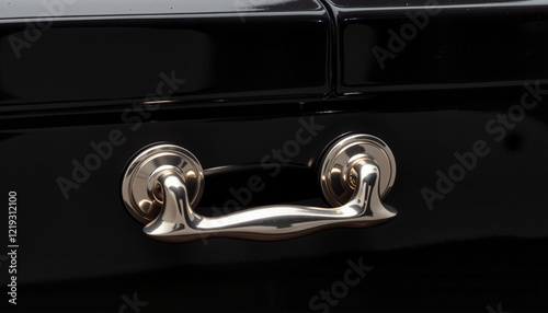 Close-up of a polished silver handle on a black casket