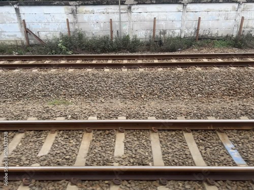 View of the railway tracks seen from inside the window of a passenger train