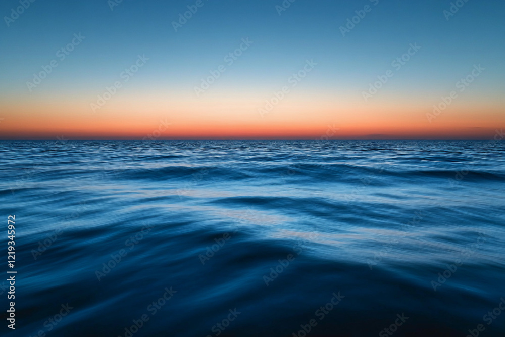 Obraz premium Sunset over calm ocean waters creates a serene atmosphere with vibrant colors on the horizon