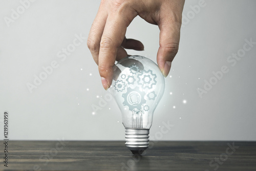 Hand holding a bright light bulb with gears. Concept of innovation of new ideas, creative analytical thinking and planning processes, knowledge.