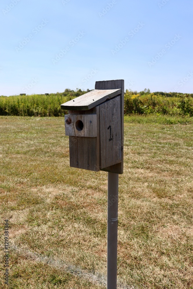 The old wood birdhouse in the field on a sunny day. The old wood birdhouse in the field on a sunny day.