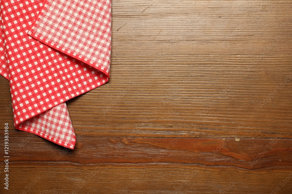 Obraz premium Red checkered tablecloth on wooden background, top view. Space for text