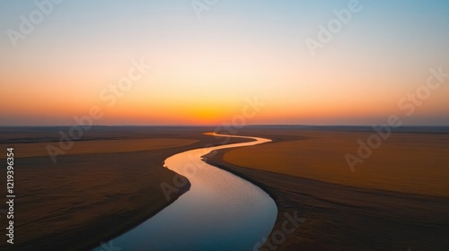 Winding river flows through golden plains under vibrant sunset s photo