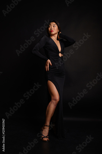 A beautiful Asian woman in an open black dress with red lipstick, standing confidently in full height, exuding elegance, style, and grace.