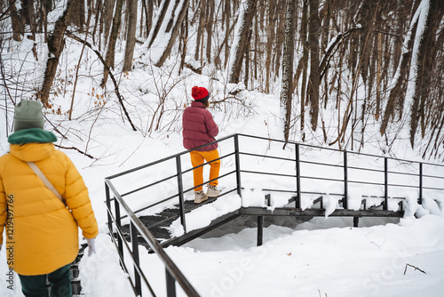 Two individuals gracefully navigate a beautifully snowcovered staircase, crafting a stunning, picturesque winter scene that undeniably captivates everyone who happens to encounter it photo