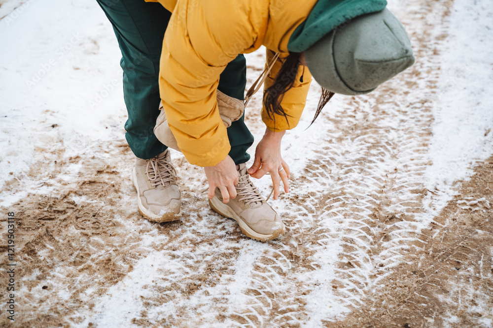 A person is kneeling down on the cold, hard ground to tie their shoes, surrounded by a stunning blanket of freshly fallen, white snow that has accumulated during this winter season A person is kneeling down on the cold, hard ground to tie their shoes, surrounded by a stunning blanket of freshly fallen, white snow that has accumulated during this winter season