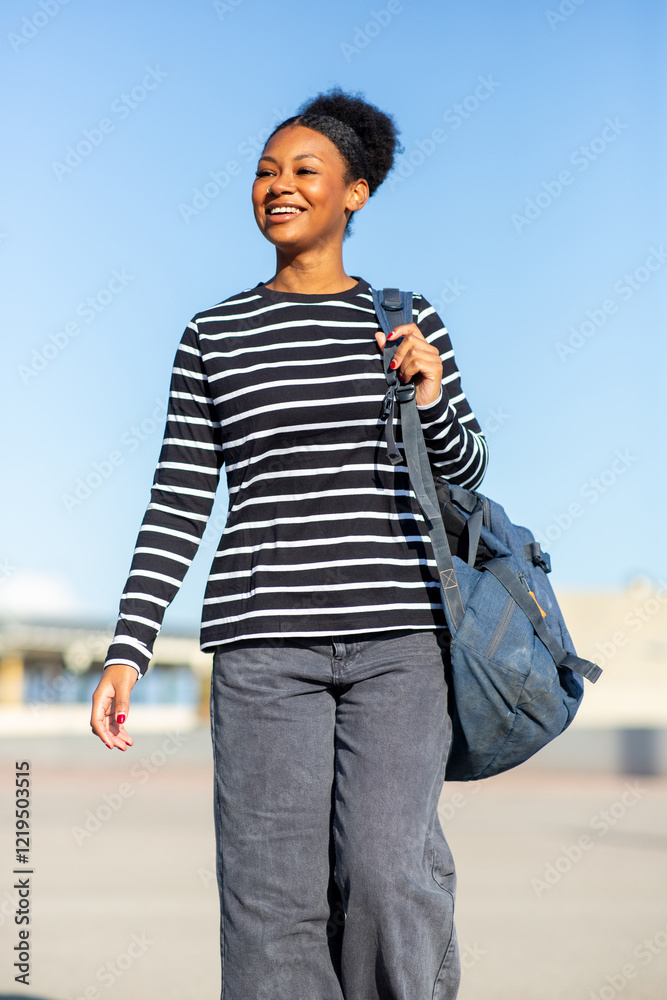 Young Latin woman smiling and carrying a backpack outdoors on a sunny day Young Latin woman smiling and carrying a backpack outdoors on a sunny day